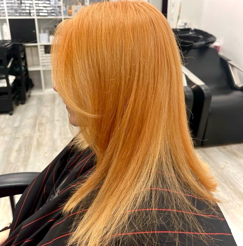 Langes Haar in einem hellen Kupferblond, glatt geföhnt, mit sichtbarem Verlauf in die Spitzen.