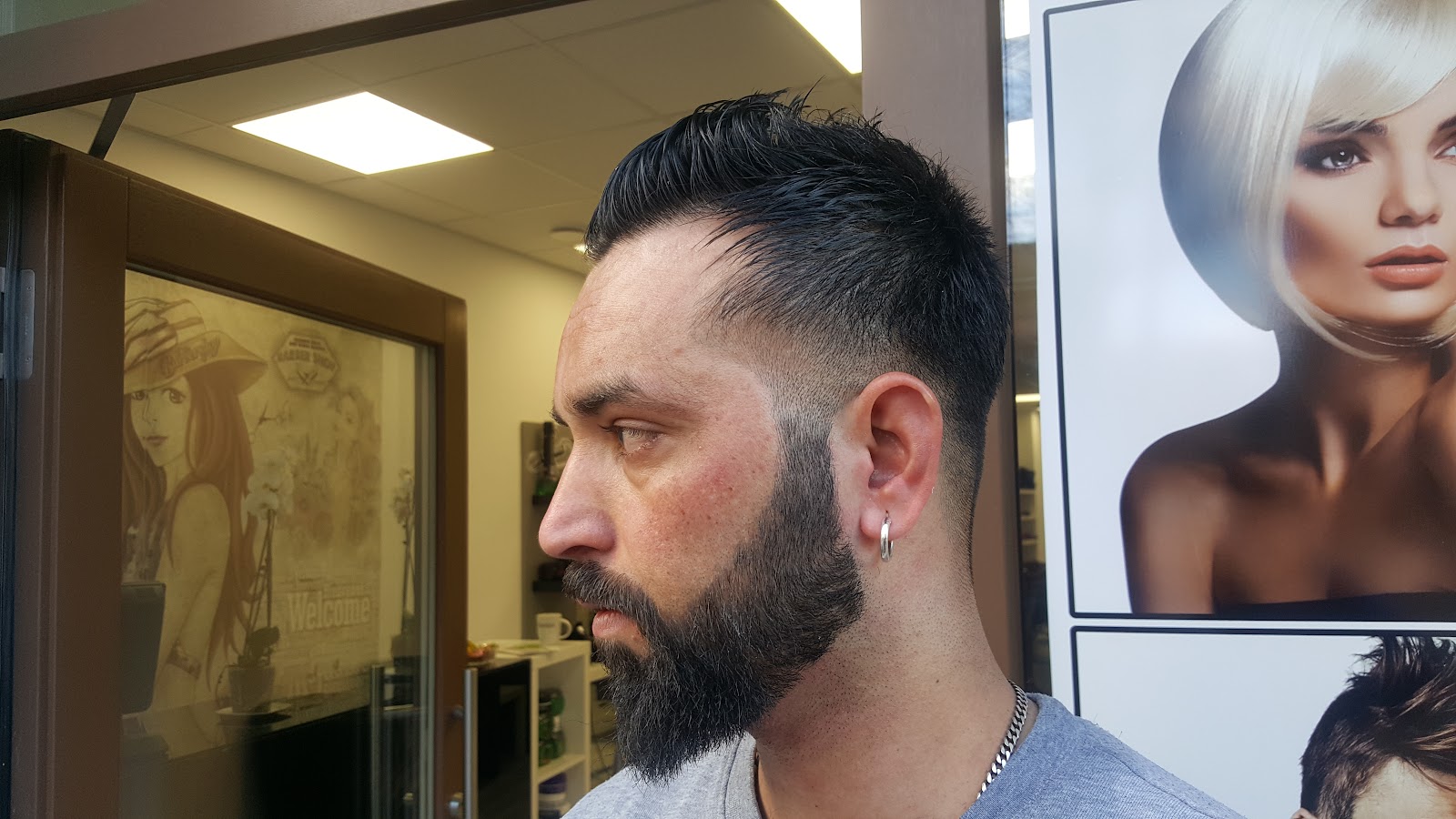 Kurzer Herrenschnitt mit Textur im Deckhaar, die Seiten weich abgesetzt, dazu ein in Form gehaltener Vollbart.