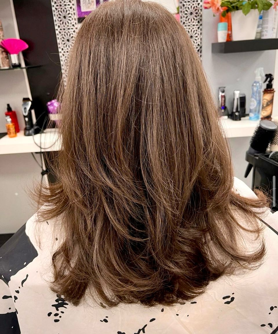 Mittelbraunes Haar in weichen Stufen, mit Volumen am Ansatz und nach außen gedrehten Spitzen geföhnt.